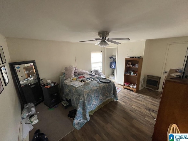 bedroom featuring ceiling fan, heating unit, and dark hardwood / wood-style flooring