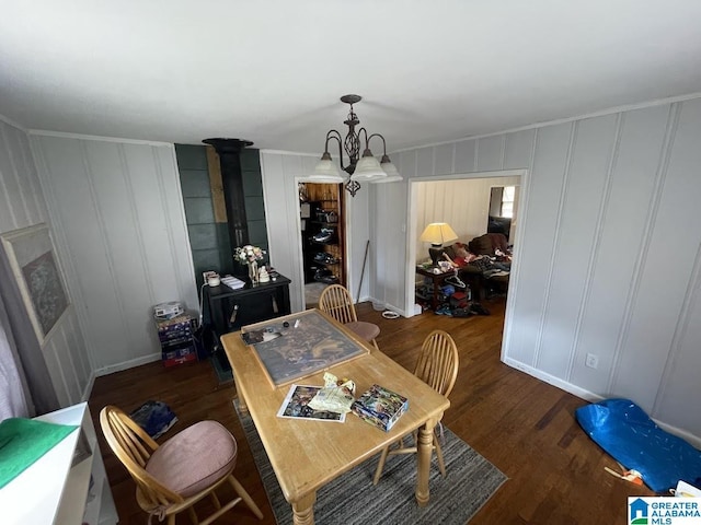 dining area featuring dark wood-type flooring, a chandelier, and a wood stove