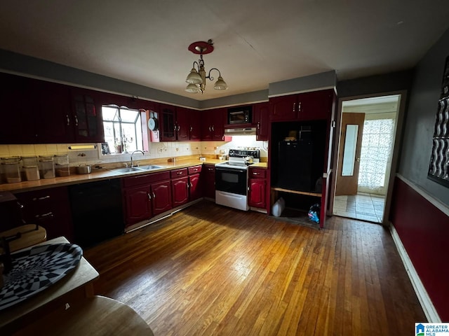 kitchen with sink, dark wood-type flooring, an inviting chandelier, black appliances, and decorative light fixtures