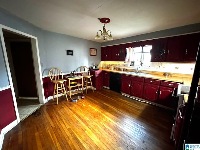 kitchen featuring sink, hanging light fixtures, dark hardwood / wood-style flooring, black dishwasher, and a notable chandelier