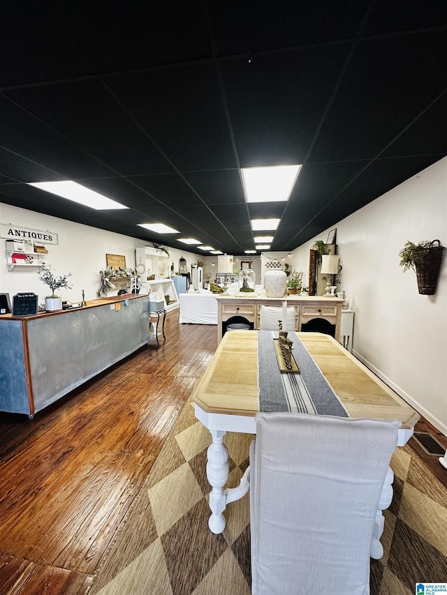 dining space featuring a drop ceiling and wood-type flooring