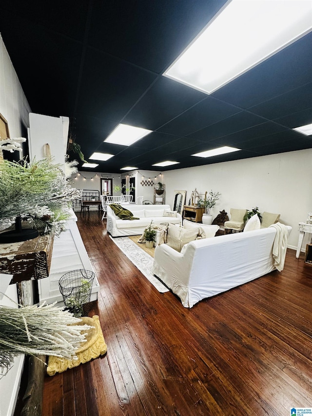 living room featuring a paneled ceiling and dark hardwood / wood-style floors