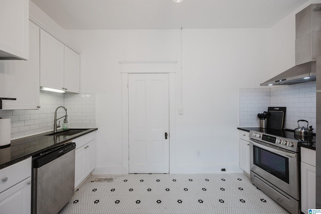 kitchen with sink, wall chimney range hood, appliances with stainless steel finishes, white cabinetry, and tasteful backsplash