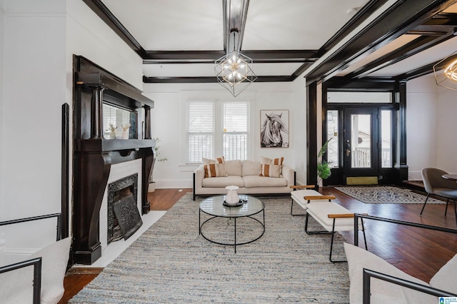 living room with beamed ceiling, ornamental molding, hardwood / wood-style floors, and a chandelier