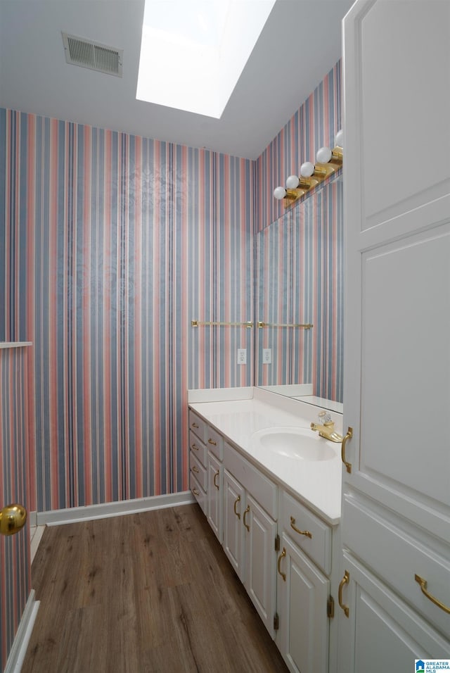 bathroom with vanity, hardwood / wood-style floors, and a skylight