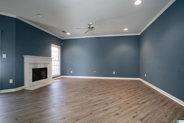 unfurnished living room featuring crown molding, light hardwood / wood-style flooring, a premium fireplace, and ceiling fan