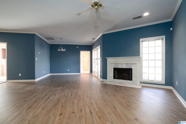 unfurnished living room featuring hardwood / wood-style floors, crown molding, ceiling fan with notable chandelier, and a premium fireplace