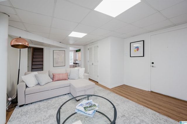 living room with a drop ceiling and light hardwood / wood-style flooring