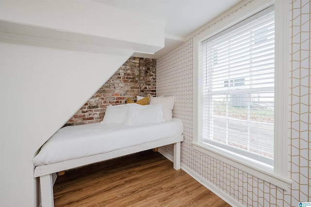 living area with brick wall and hardwood / wood-style floors