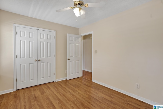 unfurnished bedroom with ceiling fan, a textured ceiling, a closet, and light wood-type flooring