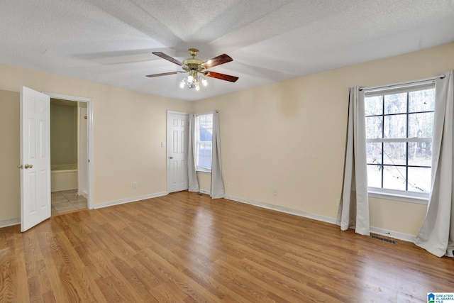 spare room with ceiling fan, a textured ceiling, and light wood-type flooring