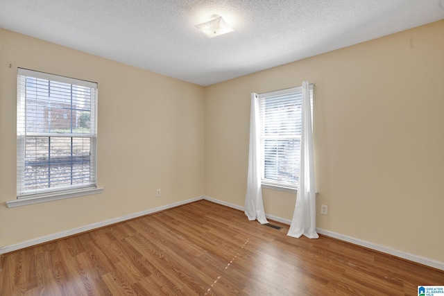 empty room with hardwood / wood-style floors and a textured ceiling