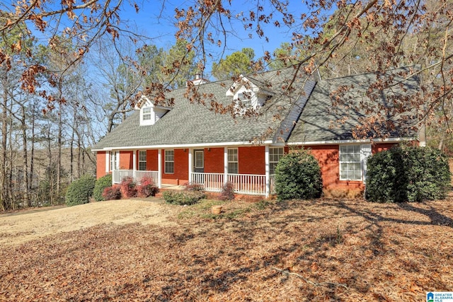 cape cod house featuring a porch and a front lawn