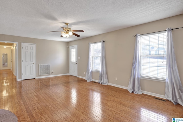 empty room featuring ceiling fan, a textured ceiling, and light wood-type flooring