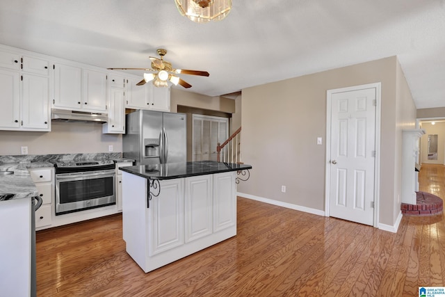 kitchen featuring white cabinetry, wood-type flooring, a center island, appliances with stainless steel finishes, and ceiling fan