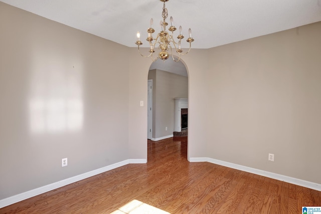 unfurnished room with hardwood / wood-style floors and a notable chandelier