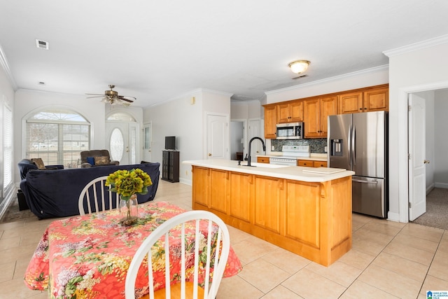 kitchen featuring tasteful backsplash, crown molding, a center island with sink, light tile patterned floors, and stainless steel appliances