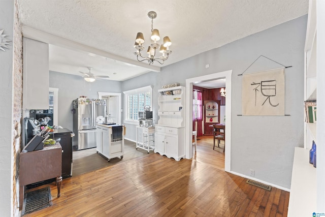 interior space with stainless steel refrigerator with ice dispenser, white cabinetry, wood-type flooring, and a textured ceiling