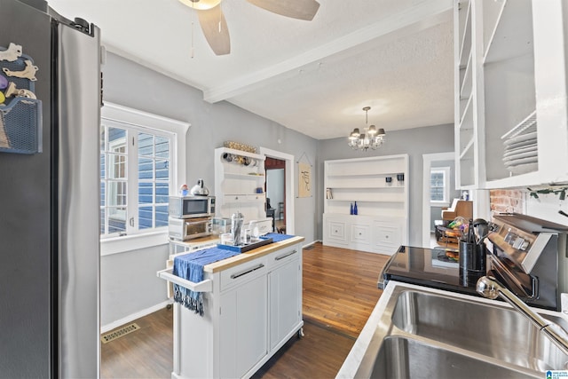 kitchen with dark wood-type flooring, hanging light fixtures, stainless steel appliances, white cabinets, and beamed ceiling