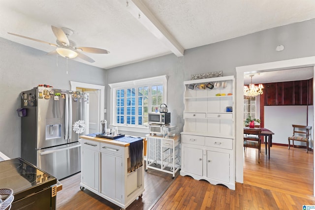 kitchen with appliances with stainless steel finishes, dark hardwood / wood-style floors, beam ceiling, and white cabinets