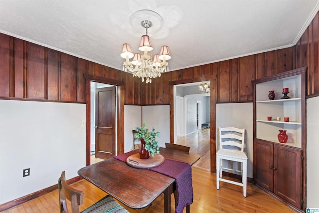 dining space featuring an inviting chandelier, crown molding, and light wood-type flooring