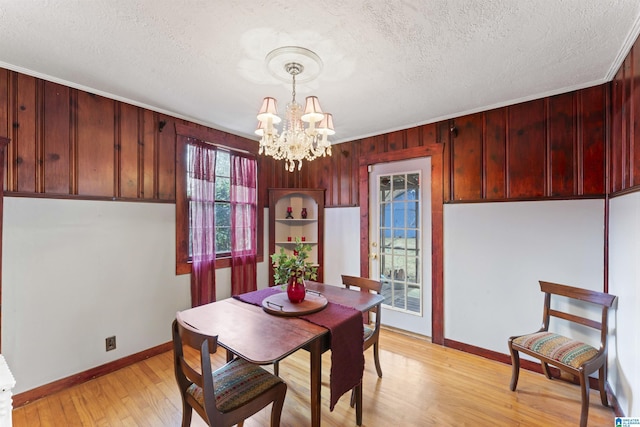 dining space featuring a notable chandelier, a textured ceiling, and light hardwood / wood-style floors