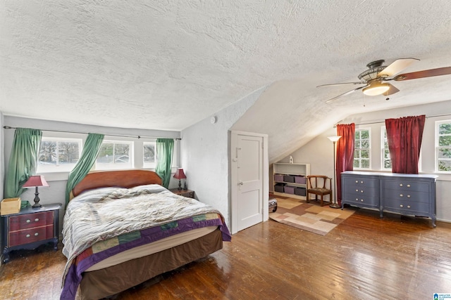 bedroom with a textured ceiling, vaulted ceiling, dark hardwood / wood-style floors, and ceiling fan