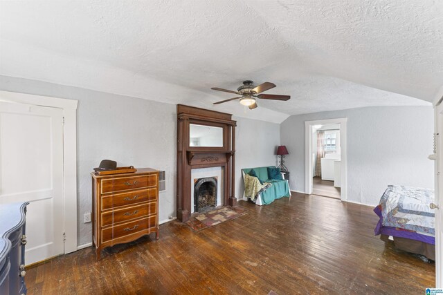 living room featuring vaulted ceiling, dark wood-type flooring, a textured ceiling, and ceiling fan