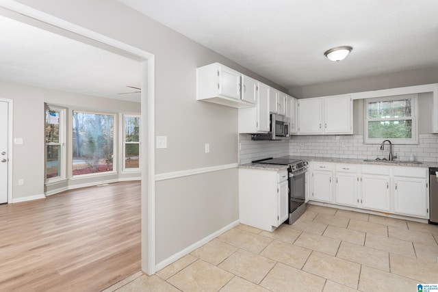 kitchen featuring sink, white cabinetry, stainless steel appliances, light stone countertops, and backsplash