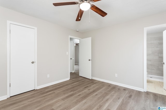 unfurnished bedroom with ceiling fan, light wood-type flooring, and ensuite bath