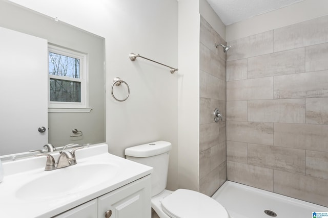 bathroom featuring vanity, toilet, and a tile shower