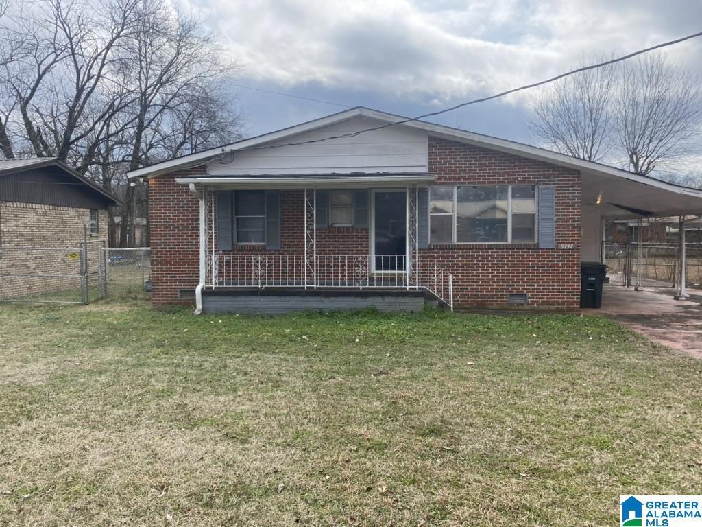 view of front of home featuring a front lawn, a carport, and covered porch