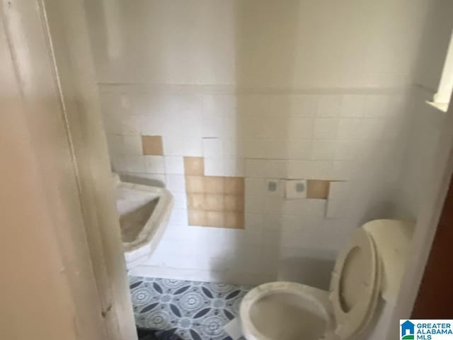 bathroom with tile walls, tile patterned flooring, and toilet