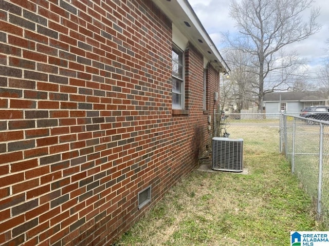 view of side of property featuring central AC and a yard