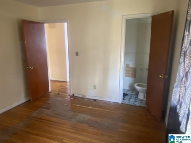 unfurnished bedroom featuring connected bathroom and hardwood / wood-style flooring