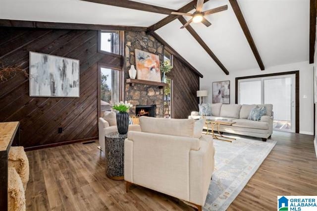 living room with hardwood / wood-style flooring, vaulted ceiling with beams, a fireplace, and wood walls