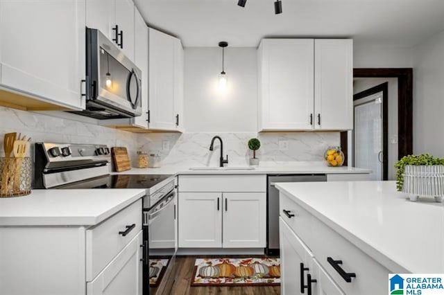 kitchen featuring appliances with stainless steel finishes, pendant lighting, white cabinetry, sink, and decorative backsplash