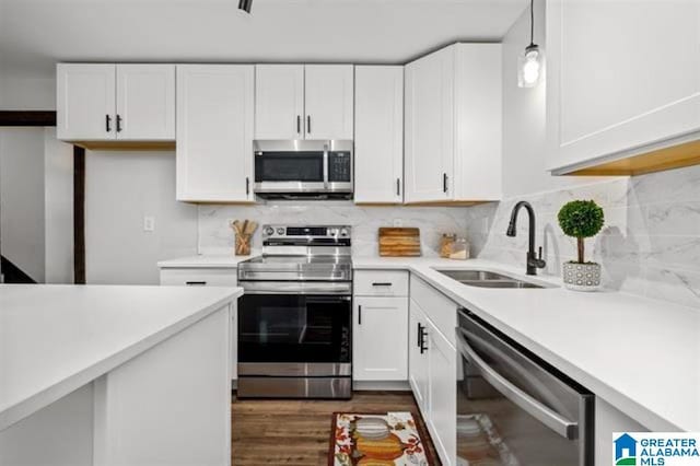 kitchen with hanging light fixtures, appliances with stainless steel finishes, sink, and white cabinets