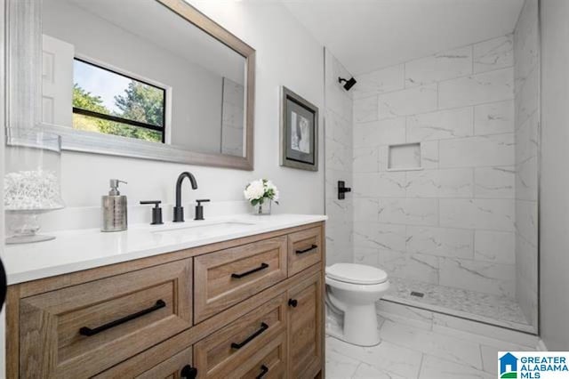 bathroom with tiled shower, vanity, and toilet