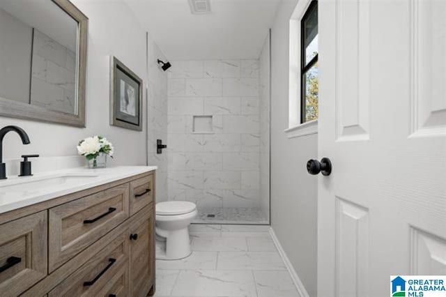 bathroom with vanity, tiled shower, and toilet