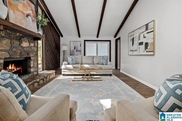 living room with hardwood / wood-style flooring, a stone fireplace, and lofted ceiling with beams