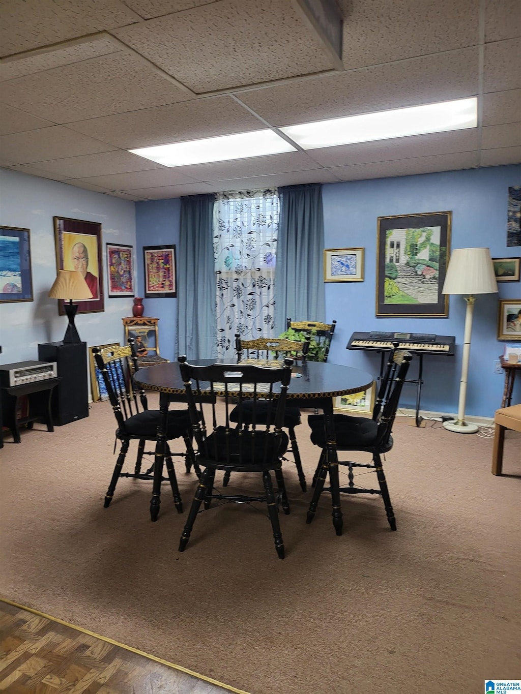 carpeted dining area with a paneled ceiling