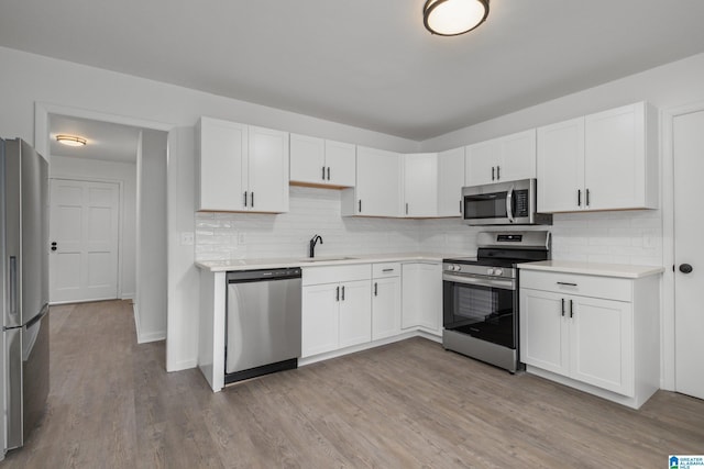 kitchen with white cabinetry, stainless steel appliances, sink, and light wood-type flooring