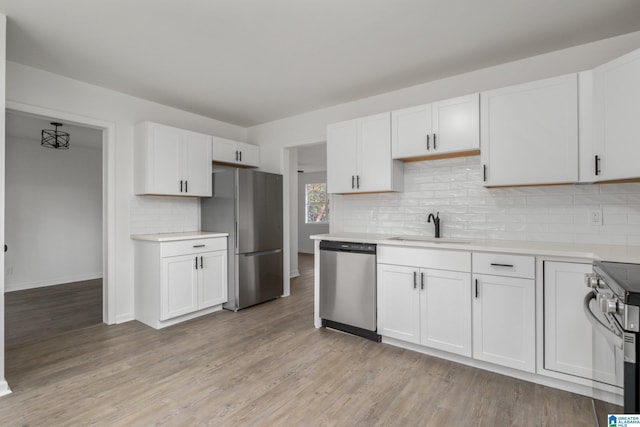 kitchen featuring tasteful backsplash, white cabinetry, sink, light hardwood / wood-style floors, and stainless steel appliances