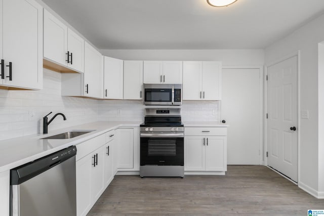 kitchen featuring appliances with stainless steel finishes, sink, light hardwood / wood-style flooring, and white cabinets