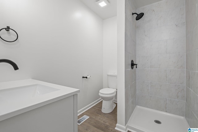 bathroom featuring tiled shower, wood-type flooring, toilet, and vanity