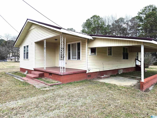 rear view of property featuring a yard and covered porch