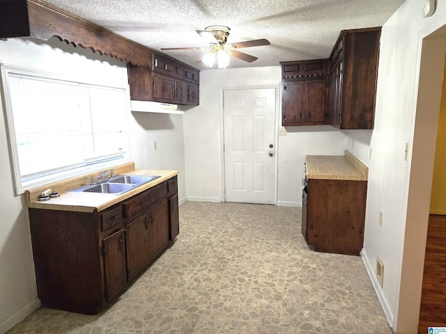 kitchen with sink, a textured ceiling, dark brown cabinets, and ceiling fan