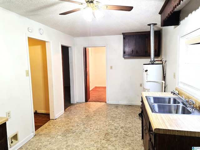 kitchen with gas water heater, sink, ceiling fan, dark brown cabinetry, and a textured ceiling