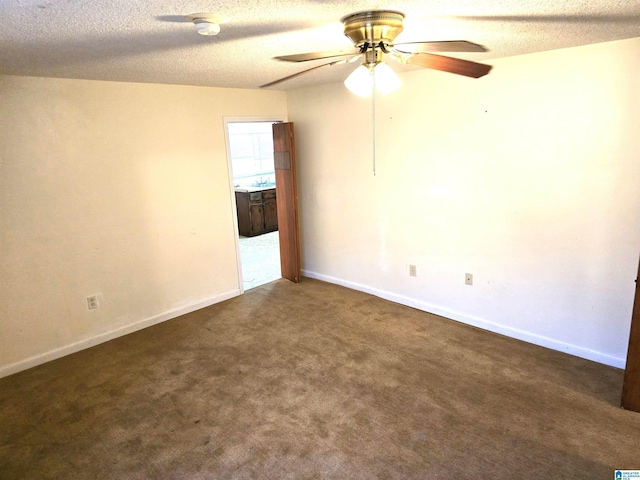 empty room featuring ceiling fan, a textured ceiling, and dark carpet